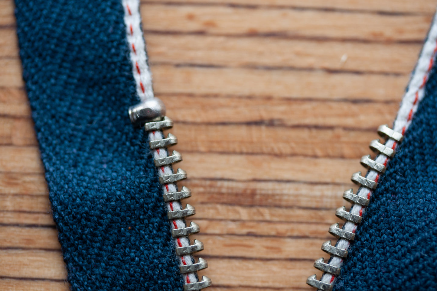 Z-002 Jeans-Reißverschluss aus Edelstahl – offene Zahnreihe mit weiß-roter Webkante auf blauem Band, Detailansicht